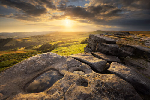 Chasing the Light: Sunset puddles on Stanage Edge. Dramatic golden hour light under a moody sky on Stanage Edge, looking towards the Hope Valley.